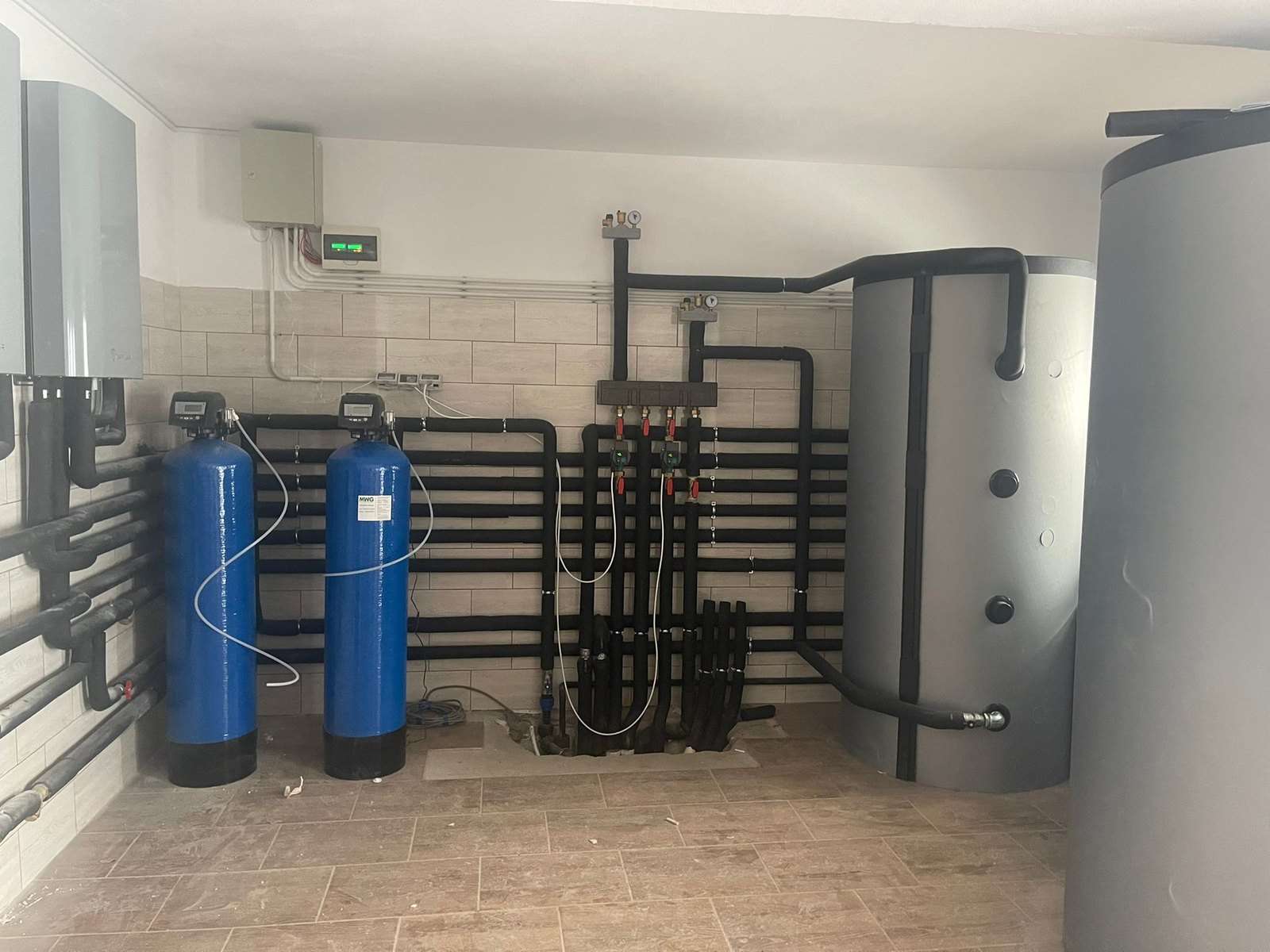 Teknikrummet i et hus med en af vores varmepumper: buffertank, varmtvandsbeholder og vandbehandling