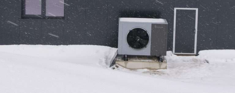 Pompa di calore aria-acqua a propano in funzione sotto una nevicata, con la neve sul coperchio